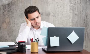 pekerja dengan ekspresi lelah dan kehilangan minat untuk bekerja di depan laptop